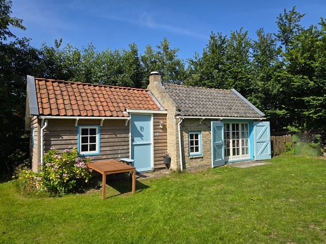 Voorkant van het huisje met lichtblauwe deuren en luiken