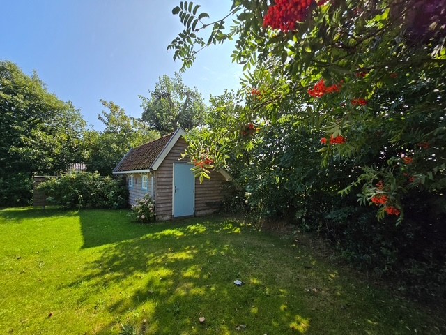 De buitenkamer met lichtblauwe deur in de tuin